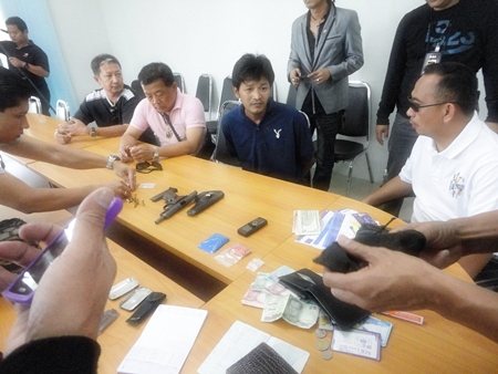 Saksit Suwadit (seated center) is brought in for questioning after police nailed him in a sting operation.